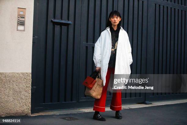 Chinese model Xie Chaoyu wears an oversized round white coat, a black print top, red flare pants, and black shoes after the Missoni show during Milan...