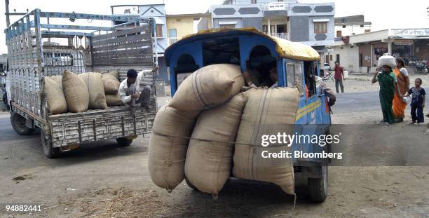 Farmers transport their sacks of grain in trucks and on the back of a three-wheeled taxi to be sold May 24, 2005 at a wholesaler in the village of...