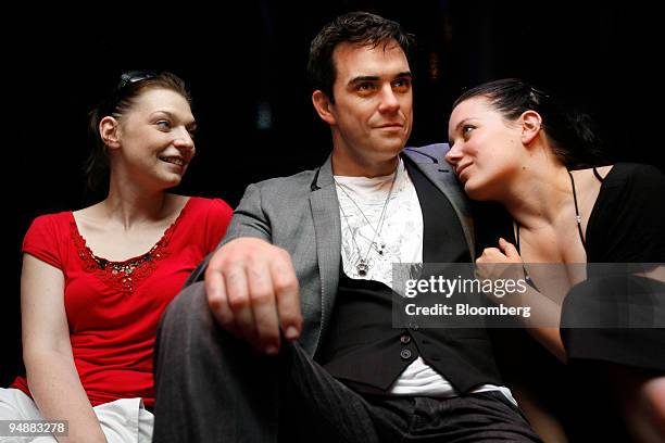 Visitors pose with a wax figure of Robbie Williams, UK singer, on display at Madame Tussauds prior to the exhibition's public opening, in Berlin,...