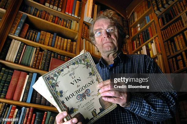 Alphonse Chavroche owner of an antiquarian bookshop, poses with an early guide to the local wines of the Burgundy region in his shop in Beaune,...