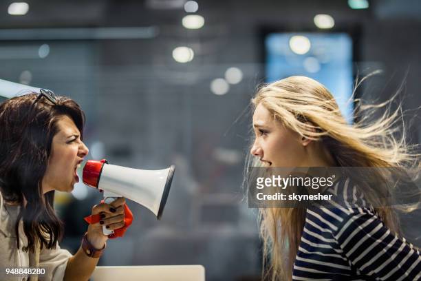 profile view of angry female manager yelling at her colleague through megaphone. - bossy stock pictures, royalty-free photos & images