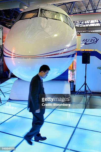 An employee of China Aviation Industry Corp. I walks past a mockup of the company's ARJ21 regional passenger plane at the Asian Aerospace 2004 show...