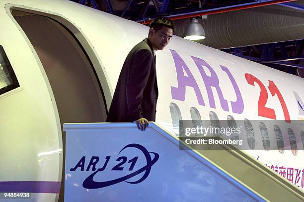 An employee of China Aviation Industry Corp. I exits a mockup of the company's ARJ21 regional passenger plane at the Asian Aerospace 2004 show in...