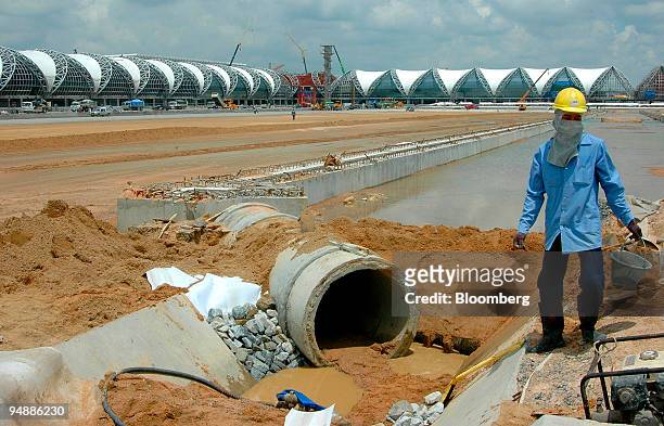 Workman carries a bucket near a drainage pipe at the construction site of Bangkok's new Suvarnabhumi International Airport Monday, September 20,...
