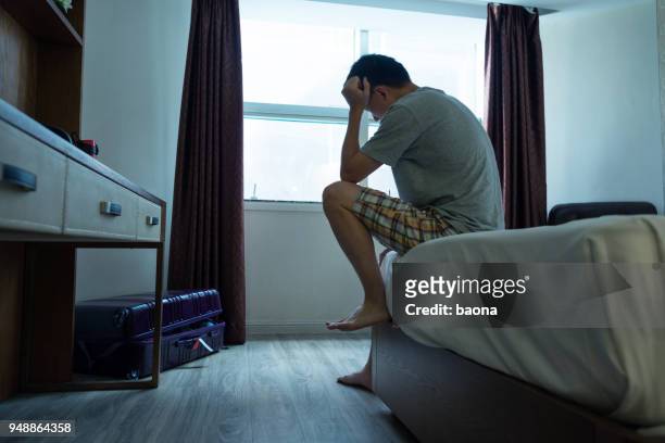 man sitting on bed with head in hands - fatigue full body stock pictures, royalty-free photos & images