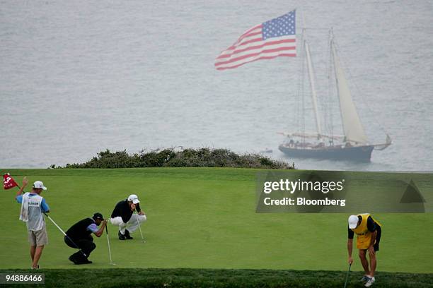 Golfer Tiger Woods and Robert Karlssson look for their shots on the 3rd hole with the Schooner America in the background on day three of the 108th...