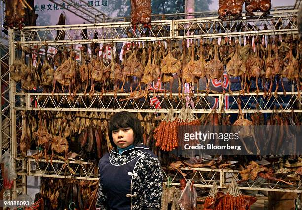 Sales person stands in front a rack of cured and salted meats at a Lunar New Year food fair in Chengdu, China, on Sunday, Jan. 27, 2008. The year of...