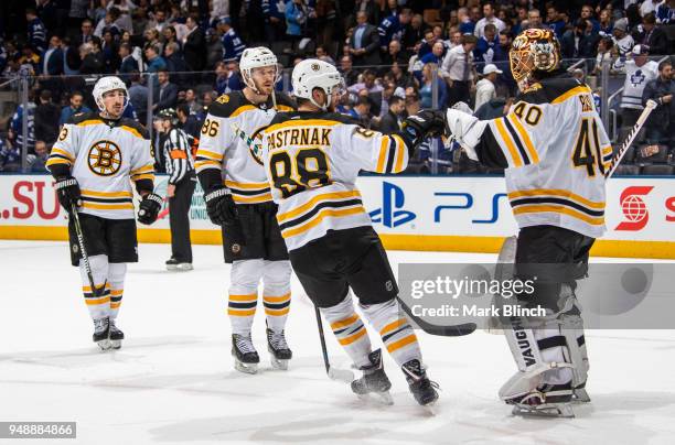 Tuukka Rask of the Boston Bruins is congratulated by teammates David Pastrnak, Kevan Miller and Brad Marchand after the Bruins defeated the Toronto...