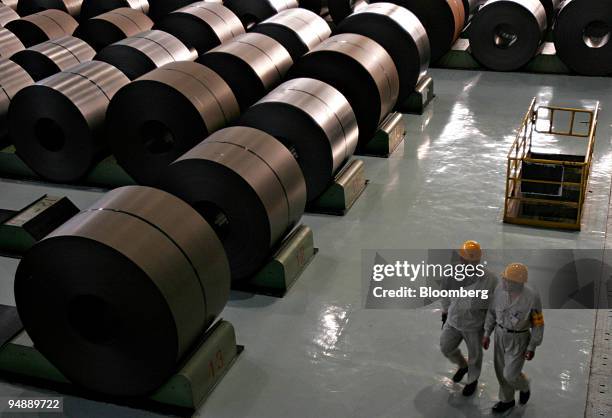 Workers walk past rolled steel at the Baosteel-NSC/Arcelor Automotive Steel Sheets Co. Plant in Shanghai, China, Tuesday, November 8, 2005. The U.S....