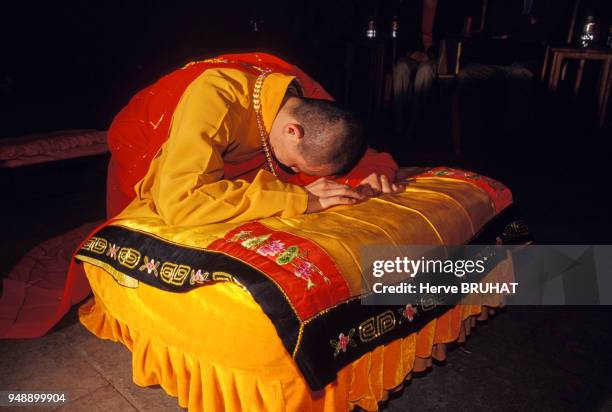 Moine priant pendant la cérémonie précédent une représentation de musique bouddhiste à Pékin, en 2002, Chine.