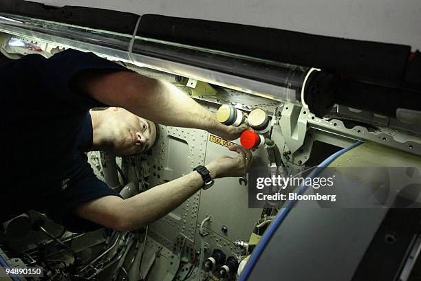 Worker makes an adjustment on a jet fighter under construction at the Saab Jas Gripen factory in Linkoeping, Sweden, Tuesday, February 10, 2004.