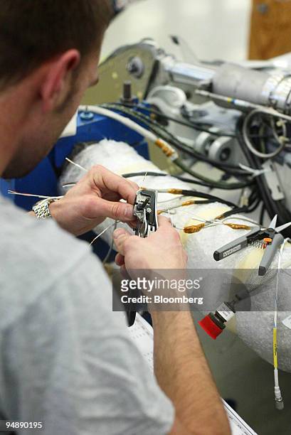 Worker installs wiring on a jet fighter under construction at the Saab Jas Gripen factory in Linkoeping, Sweden, Tuesday, February 10, 2004.