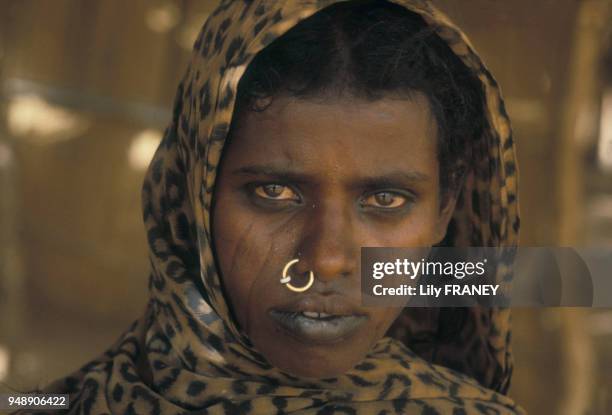 Portrait de femme tatouée avec un anneau dans le nez et un foulard sur la tête en juin 1985, à Kartoum au Soudan.