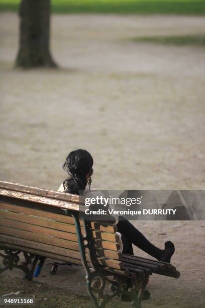 Jeune femme assise sur un banc dans un parc de la ville de Bruxelles, Belgique.