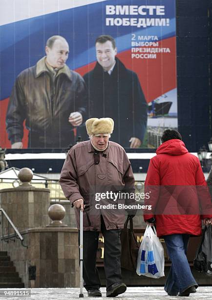 Pedestrians walk in the center of Moscow near an election poster showing Russian President Vladimir Putin and presidential candidate Dmitry Medvedev...