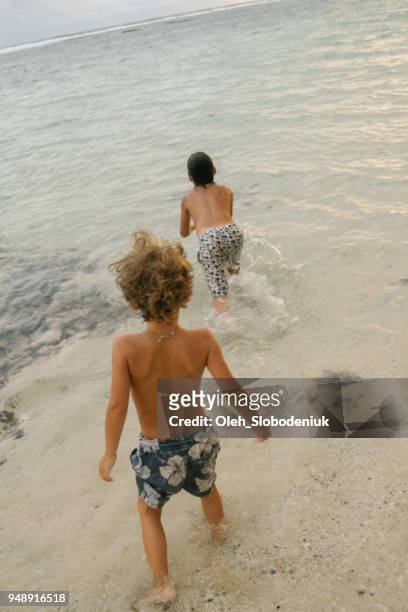 little boys playing in the sea - melasti ceremony in indonesia stock pictures, royalty-free photos & images