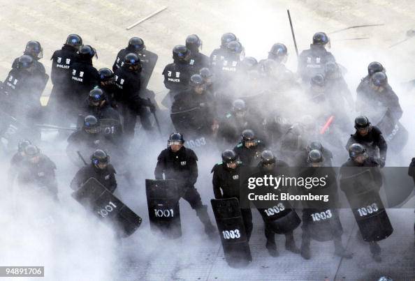 Riot police, shrouded in fire extinguisher smoke, hold a position ...