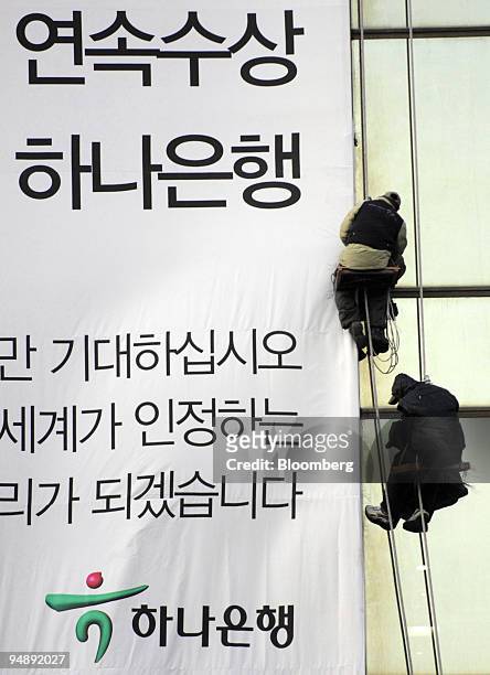 Workers display an advertising banner at a Hana Bank business center in Seoul, South Korea, on Tuesday, Feb. 12, 2008. Hana Financial Group is South...