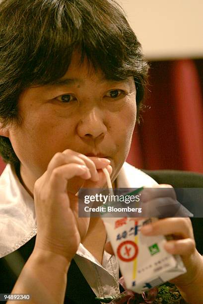 China Mengniu Dairy Co. Vice President Lu Jun drinks from a carton of her company's milk before a press conference in Hong Kong Wednesday, September...