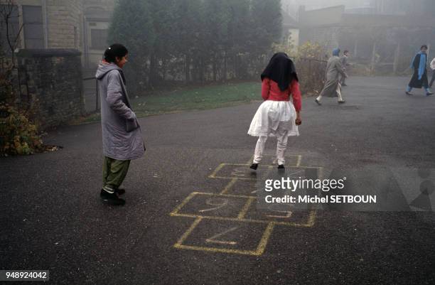 Petites filles musulmanes jouant à la marelle dans la cour d'une école publique de Batley, en 1989, Royaume-Uni.