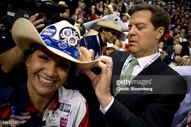 Sam Brownback, a Republican senator from Kansas, right, signs a hat for a delegate from Texas on day four of the Republican National Convention at...