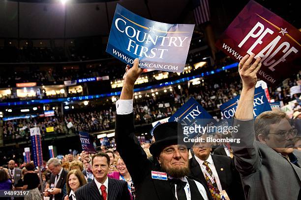 Delegate George Engelbach, center, waves a "Country First" sign on day four of the Republican National Convention at the Xcel Energy Center in St....
