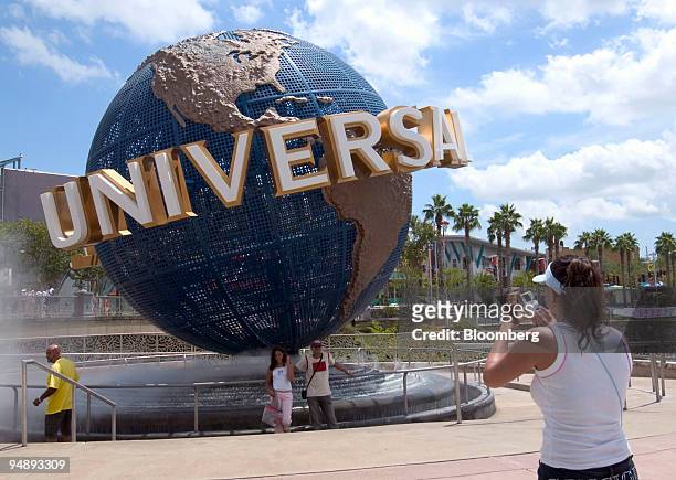 People pose for a photo with the Universal Studios globe at the entrance to the theme park in Orlando, Florida, Monday, August 30, 2004.