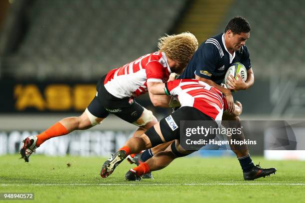 Leni Apisai of the Blues A is tackled by Willem Britz and Masakatsu Nishikawa of Japan A during the curtain raiser match ahead of the round 10 Super...