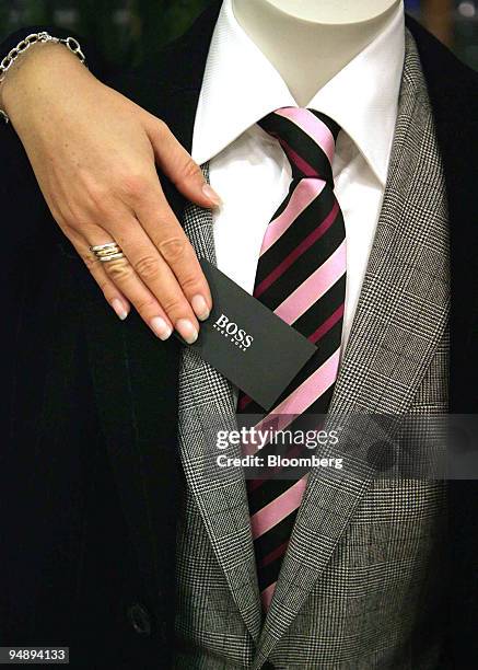 Woman adjusts the Hugo Boss label on a suit in a store in Cologne, Germany, Saturday, October 29, 2005. The company's earnings are scheduled to be...