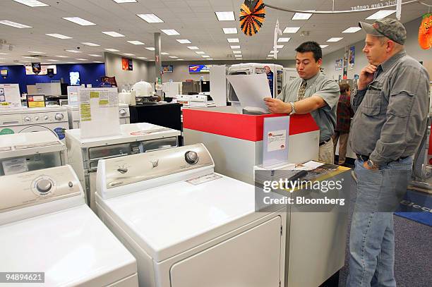 Clint Flemming, a sales associate at Bernie's Appliance, Television and Bedding, completes the sale of a deluxe microwave oven to Ed Desjarlais in...