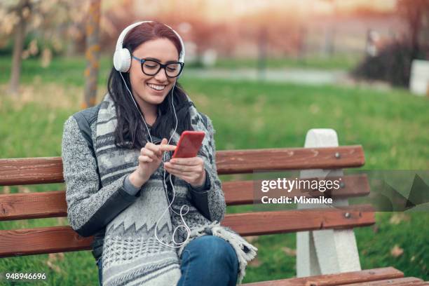 cheerful woman listening to music in the park - 2017 common good forum stock pictures, royalty-free photos & images