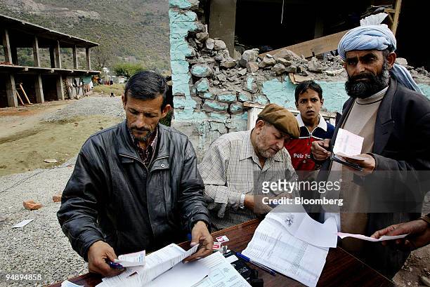 Jammu and Kashmir bank officials check documents of earthquake survivors as they open new bank accounts to deposit the first installment of relief...