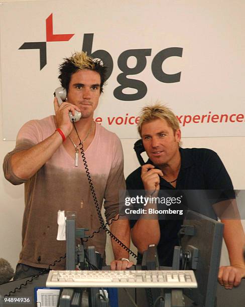 Cricketers Kevin Pietesen of England, left, and Shane Warne of Australia use the phones at the brokerage firm BGC in the city of London, Wednesday...