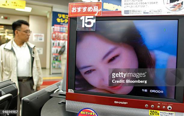 Customer inspects Sharp Corp. LCD TVs in a Tokyo electronics store Wednesday, October 26, 2005.