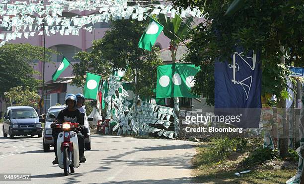 Motorcyclist drives past election posters and flags for Pan-Malaysian Islamic Party and Barisan Nasional in Kota Bharu, Kelantan, Malaysia, on...