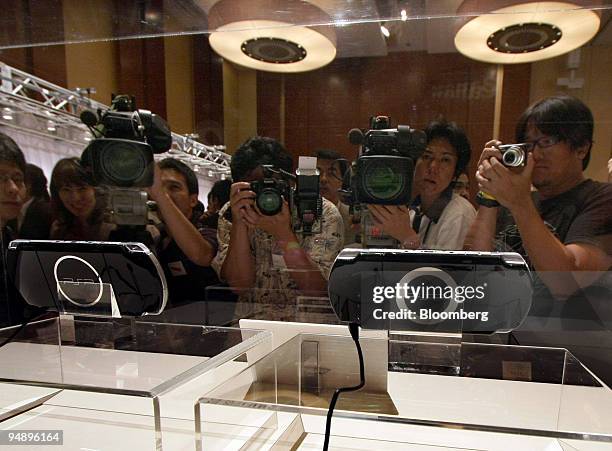 Member of the media photograph Sony Computer Entertainment Inc.'s PlayStation Portable "PSP-3000" players displayed at a news conference in Tokyo,...
