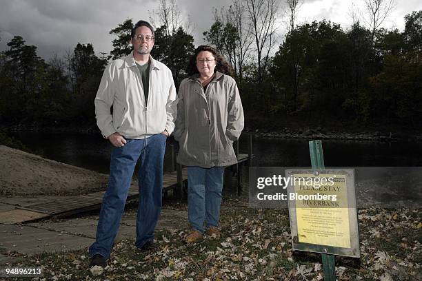 Gary Henry and his wife Kathy pose near a sign warning of elevated dioxin levels in the Tittabawassee River at Imerman Memorial Park, Saginaw,...