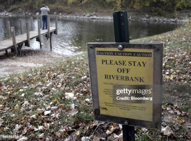 Caution sign warns visitors to stay off the riverbank because of elevated dioxin levels as Gary Henry takes a picture of the Tittabawassee River at...