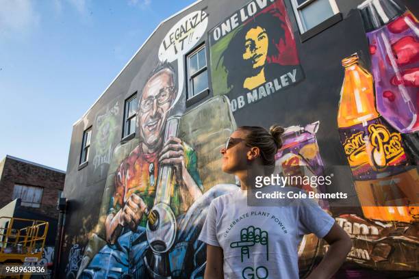 Girl in a pro cannabis shirt stands in front mural of Senator Richard Di Natale is seen in the Sydney suburb of Newtown on April 20, 2018 in Sydney,...
