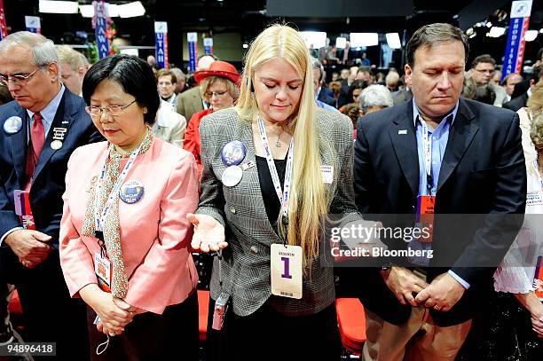 Terri Lois Gregory, a delegate from Gardner, Texas, center, takes part in a prayer during the invocation on day one of the Republican National...