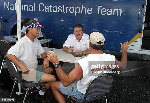 Harrison Bucklew, left, and his brother, Mitchell Bucklew, right, talk with Allstate insurance adjuster Kirk Gresham, center, at a mobile unit for...