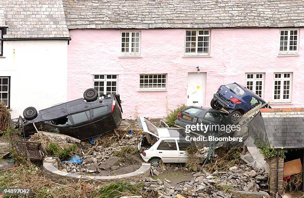 Pile of cars lie against a cottage wall in Boscastle after the small Cornish village was hit by flood waters, Tuesday August 17, 2004. U.K. Police...