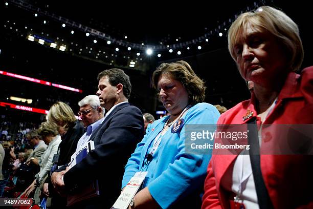 Delegates take part in a prayer during the invocation on day one of the Republican National Convention at the Xcel Center in St. Paul, Minnesota,...