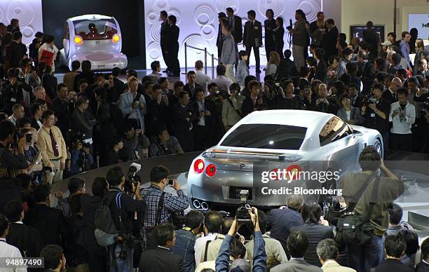 Nissan Motor Co.'s concept GT-R Proto coupe, right, and Pivo three-seat concept minicar, background left, are mobbed by photographers at the Tokyo...