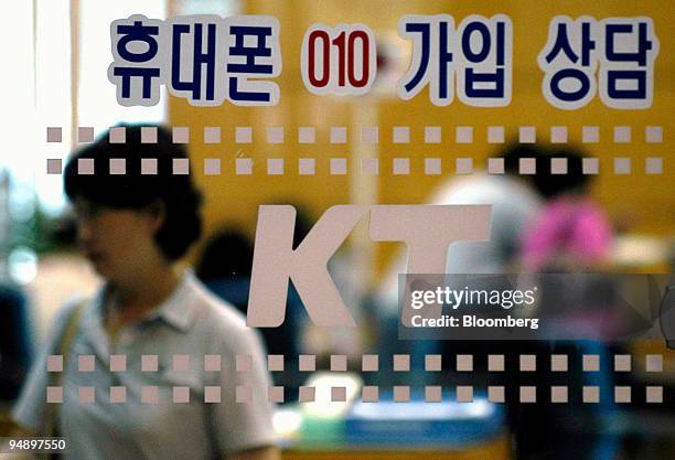 Customers are pictured at a KT Corp. Branch office in Ilsan, South Korea Friday, August 6, 2004. The glass sign advertises for a new cellular phone....