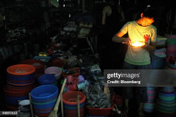 Chinese store clerk lights a candle in a blacked out portion of Shanghai, China on August 16, 2004.