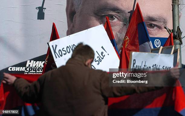 Young man holds the Serbian flag in front of a poster of the Serbian radical party leader Tomislav Nikolic at a protest in the town of Mitrovica,...