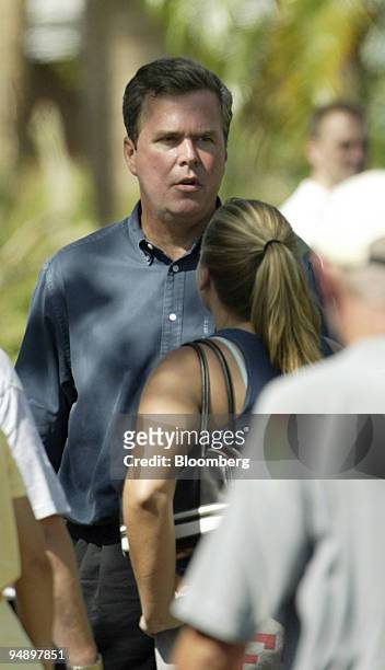 Florida Governor Jeb Bush looks at damage in Punta Gorda, Florida, as he speaks with a woman in the crowd on August 15, 2004. Punta Gorda was one of...