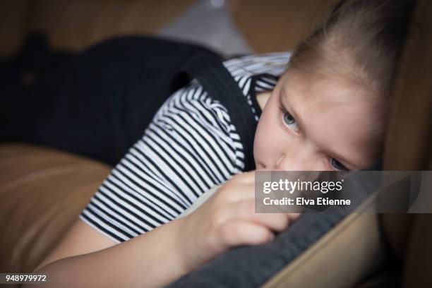 girl (8-9) lying on a sofa looking fed up - fish out of water photos et images de collection