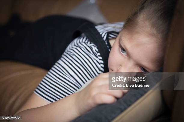 girl (8-9) lying on a sofa looking fed up - social exclusion stock pictures, royalty-free photos & images